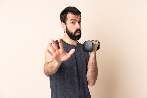 Hombre de deporte caucásico con barba haciendo levantamiento de pesas aislado