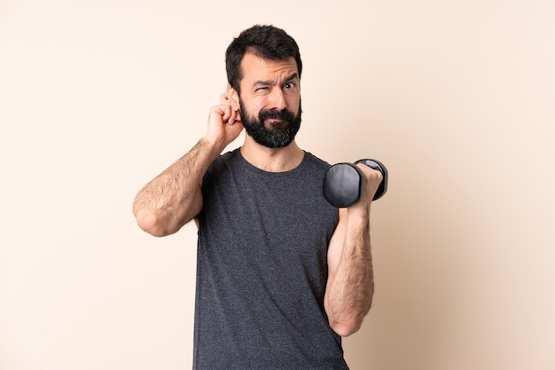 Hombre de deporte caucásico con barba haciendo levantamiento de pesas más aislado que tiene dudas