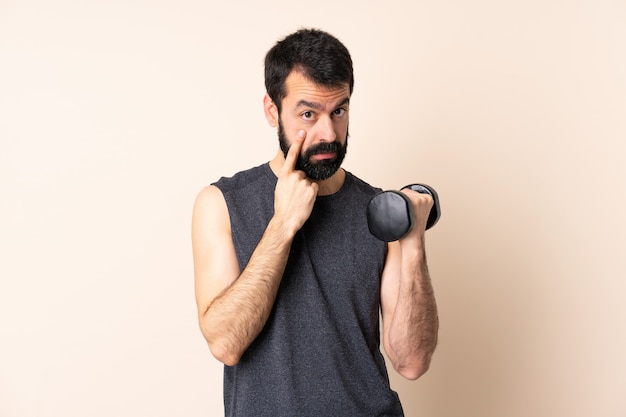 Hombre de deporte caucásico con barba haciendo pesas