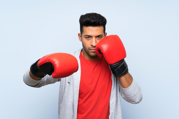 Hombre de deporte con guantes de boxeo sobre pared azul aislado
