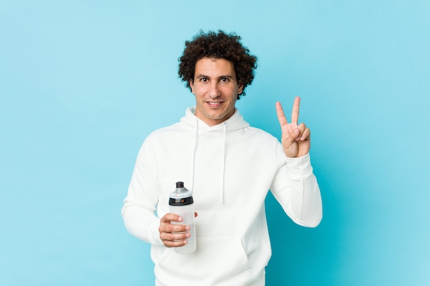 Hombre del deporte que sostiene una botella de agua que muestra el número dos con los dedos.
