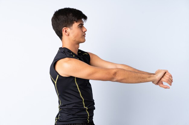 Hombre de deporte sobre fondo azul aislado estirando el brazo