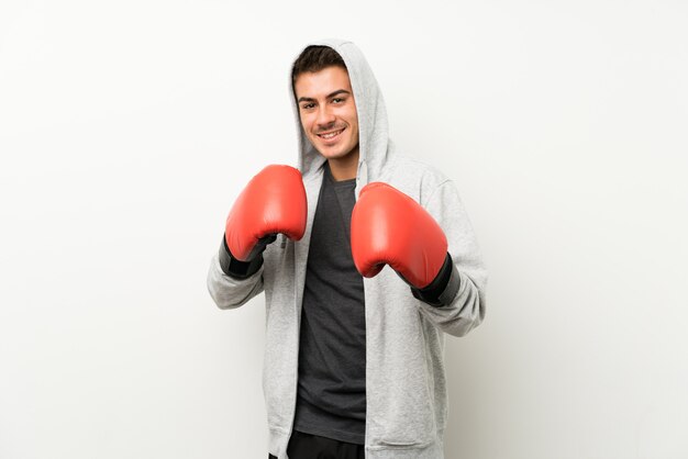 Hombre de deporte sobre pared blanca aislada con guantes de boxeo