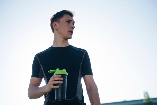 Hombre deportista cansado beber agua de una coctelera