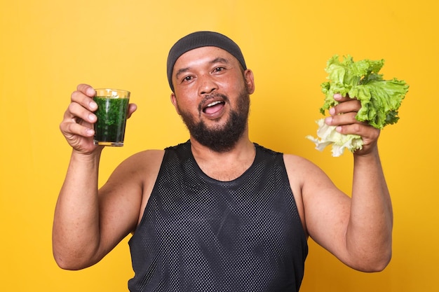 Hombre deportivo barbudo con diadema sosteniendo un vaso de jugo y verduras saludables Dieta y comida saludable