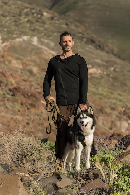 Hombre deportivo y confiado con perro en las rocas