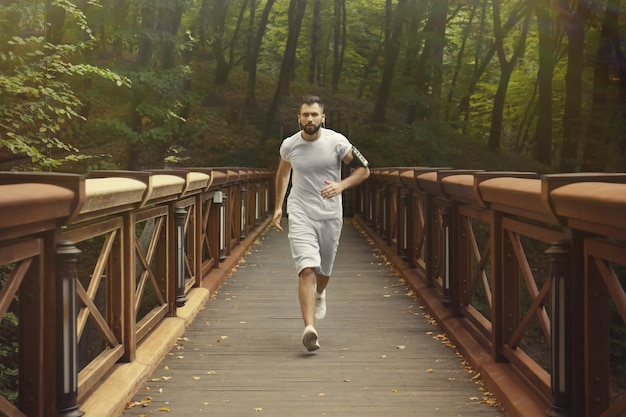 Hombre deportivo corriendo por el puente en el parque