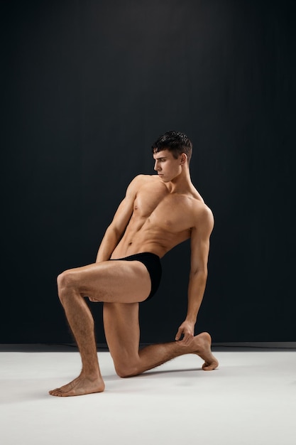 Hombre deportivo con un cuerpo desnudo pumpedup posando sobre su rodilla