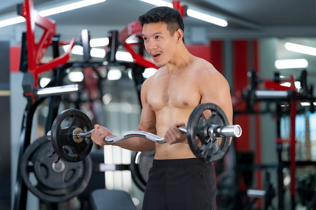 Hombre deportivo entrenando con una pesada barra en el gimnasio