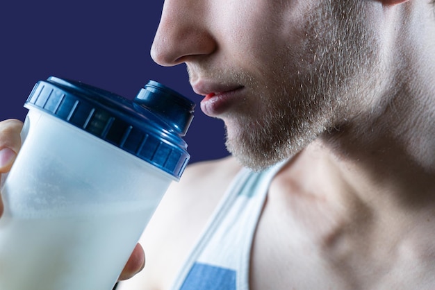 El hombre deportivo flaco sosteniendo una coctelera mientras entrena