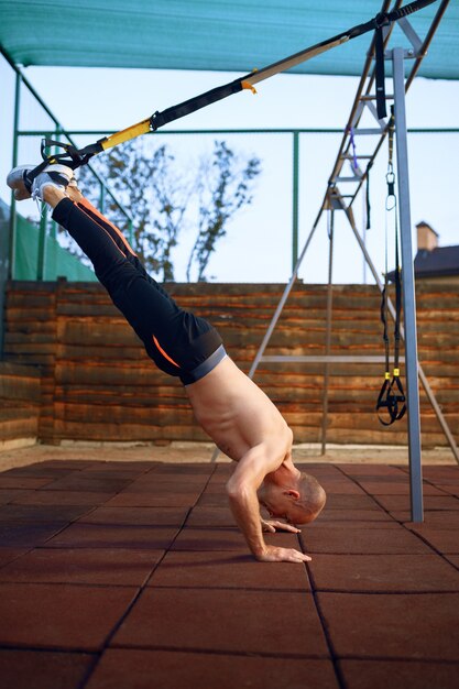 Hombre deportivo haciendo ejercicio con cuerdas en el campo de deportes al aire libre