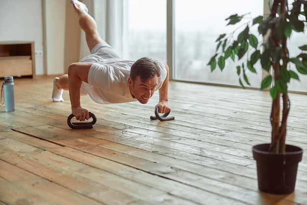 Hombre deportivo haciendo ejercicio de gran alcance en casa