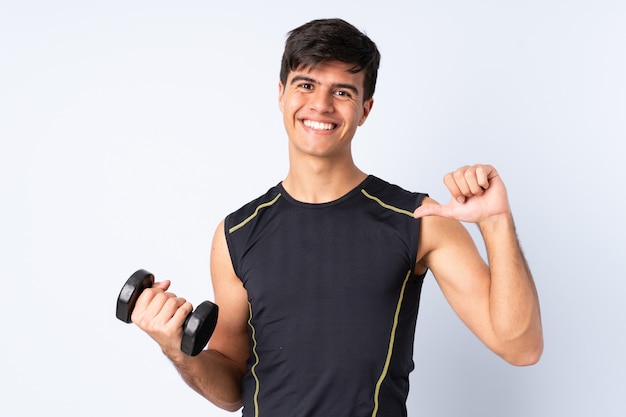 Hombre deportivo haciendo levantamiento de pesas sobre pared azul orgulloso y satisfecho