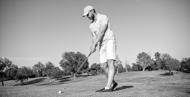 Hombre deportivo jugando al golf en campo de golf de hierba verde