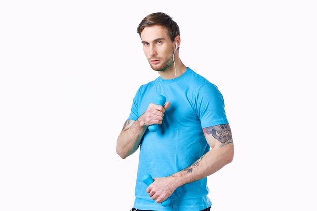 Hombre deportivo con mancuernas azules sobre fondo claro vista recortada