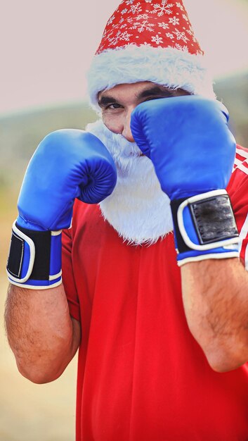 Hombre deportivo con ropa de santa claus y guantes de boxeo al aire libre