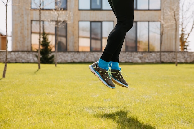 Hombre deportivo saltando sobre la hierba verde al aire libre Primer plano de las piernas masculinas en zapatillas de deporte