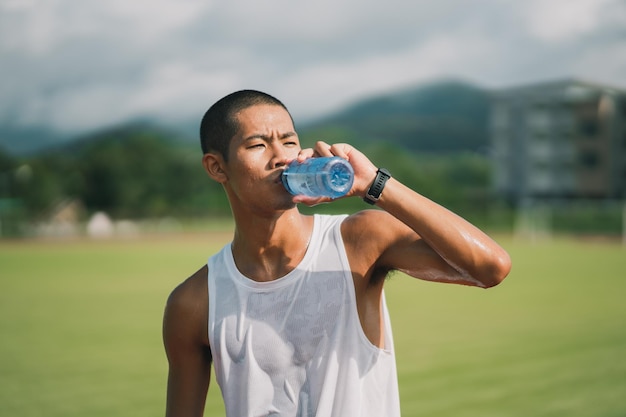 Hombre deportivo sostenga una botella de agua corredor cansado y sediento después de correr entrenamiento bebiendo agua Concepto de hombre deportivo