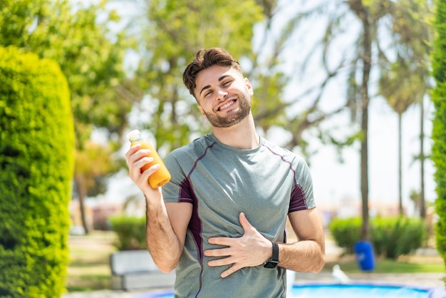 Foto hombre deportivo sosteniendo un jugo de naranja al aire libre