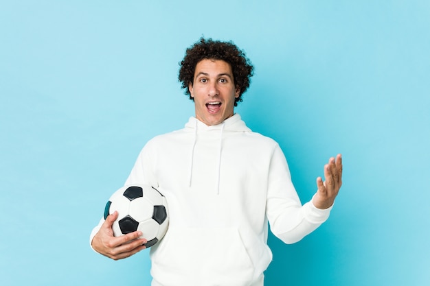 Hombre deportivo sosteniendo una pelota de fútbol celebrando una victoria o éxito