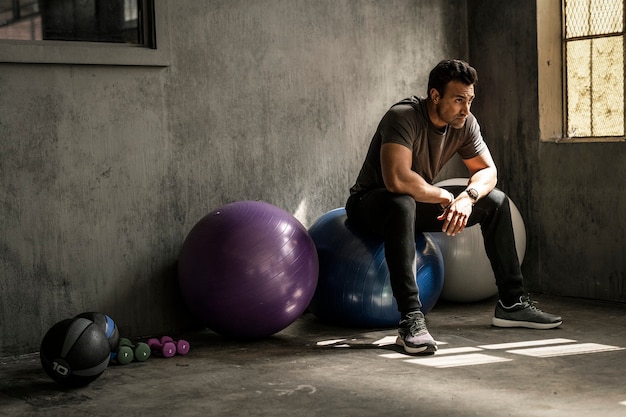 Hombre deportivo tener un descanso en una pelota de fitness