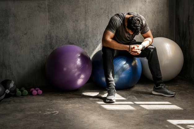 Hombre deportivo tener un descanso en una pelota de fitness