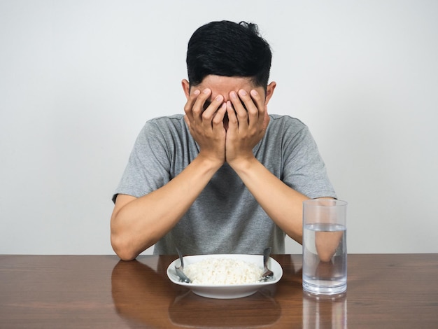 Hombre deprimido cerca de la cara sentarse con la cena en la mesa