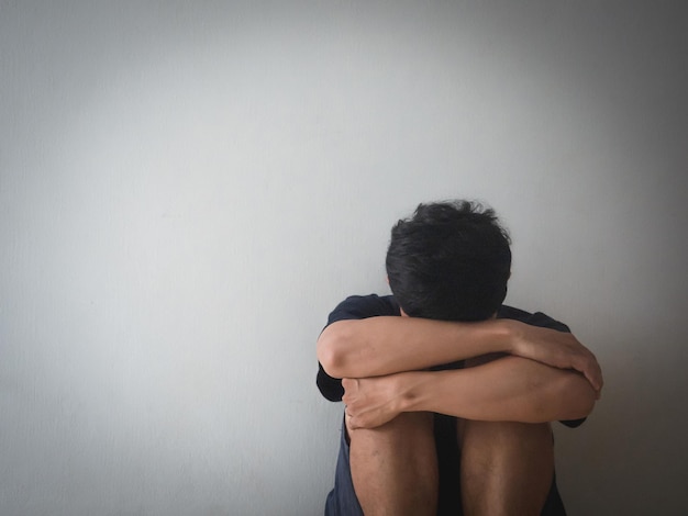 Foto el hombre deprimido sentado en la pared se siente desesperanzado con la vida