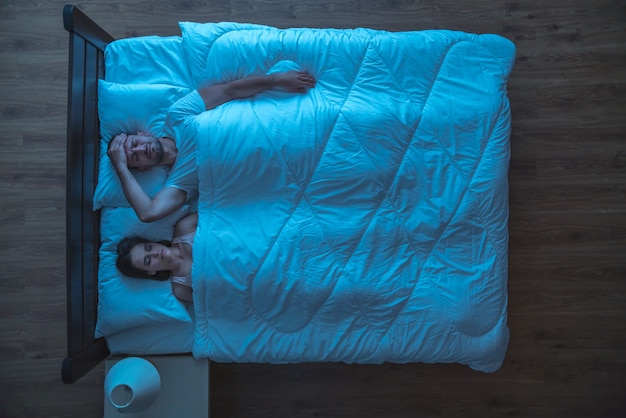 El hombre deprimido yacía cerca de una mujer. tarde por la noche. vista desde arriba