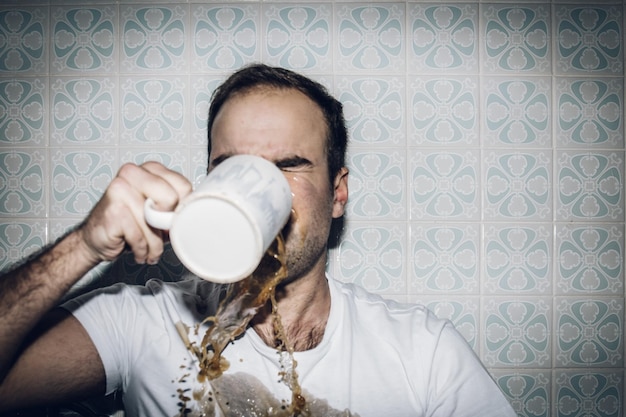 Foto hombre derramando café mientras bebe en casa