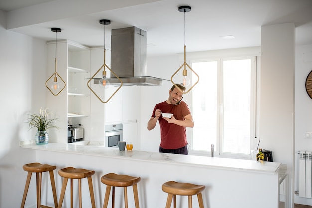 Foto hombre desayunando con teléfono móvil