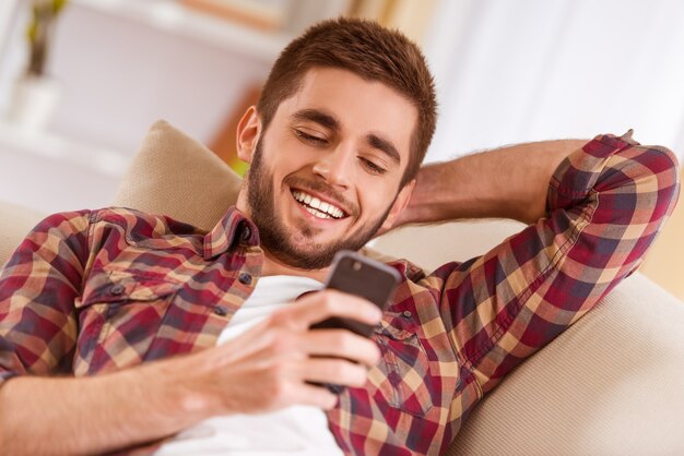 Un hombre descansa en casa y mira el teléfono.