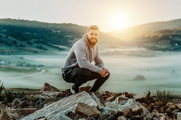 El hombre descansa en la cima del monte después del entrenamiento matutino