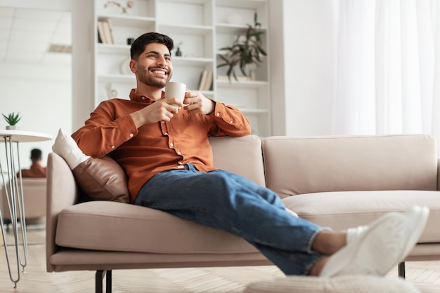 Hombre descansando en casa en el sofá tomando café