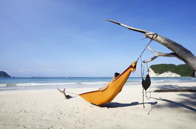 Foto hombre descansando en una hamaca en la playa de tarimbang