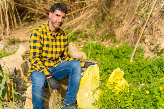 Hombre descansando de recoger basura en un bosque Ecología naturaleza limpia de plásticos