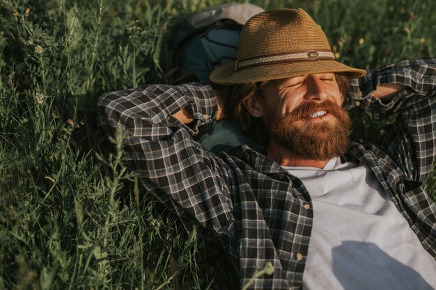 Hombre descansando sobre la hierba verde durante el viaje en día soleado