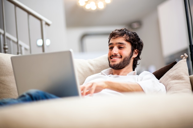 Hombre descansando en el sofá con su computadora portátil