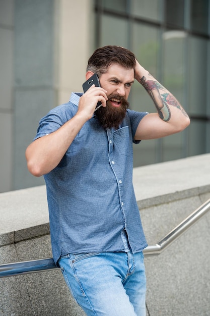 hombre desconcertado hablando en teléfono inteligente afuera hombre hablando en teléfono móvil en la calle foto de hombre hablando en smartphone hombre hablando en móvil afuera