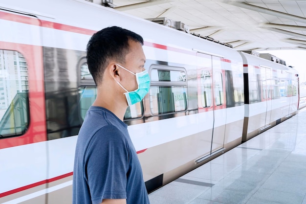 Hombre desconocido de pie en la estación de tren con máscara