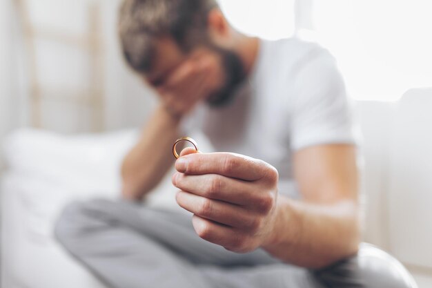 Hombre desconsolado que sostiene un anillo de bodas