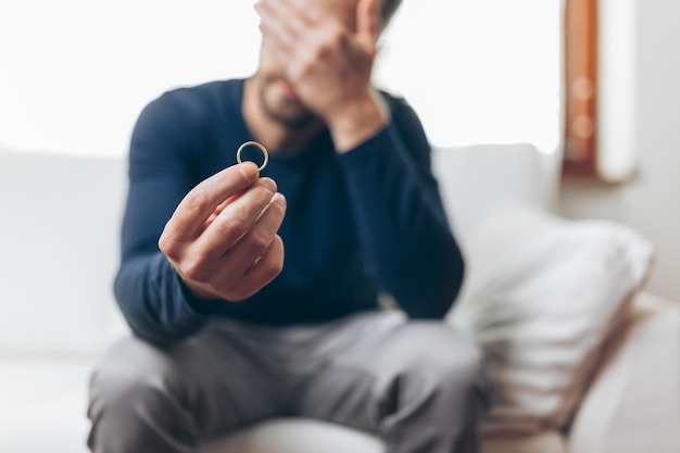 Foto hombre desconsolado que sostiene un anillo de bodas