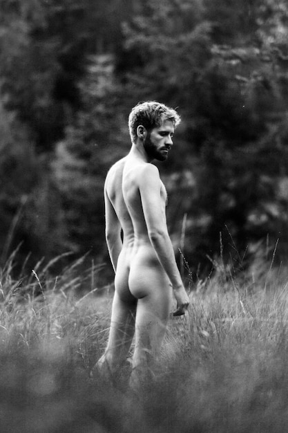 Foto hombre desnudo sin camisa de pie junto a las plantas