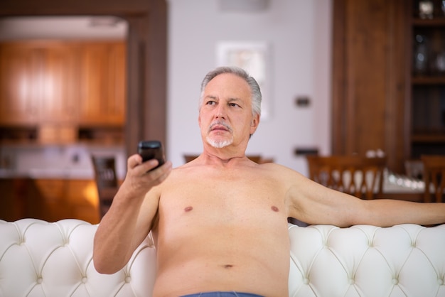 Hombre desnudo relajándose y viendo la televisión en casa