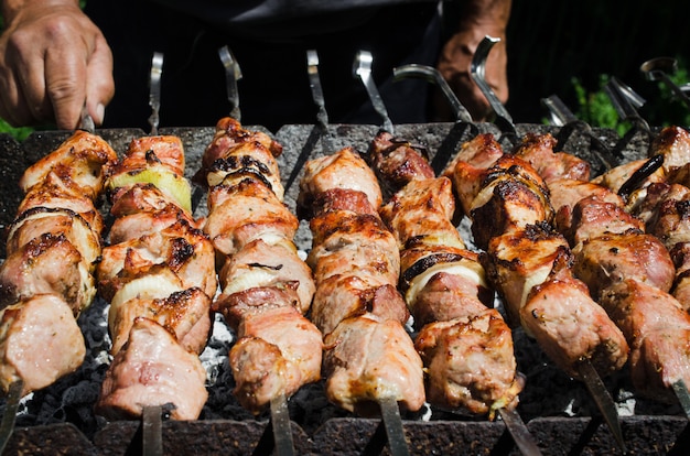 El hombre se desplaza Brocheta con jugosos trozos de carne de cerdo o carne de res en una parrilla.