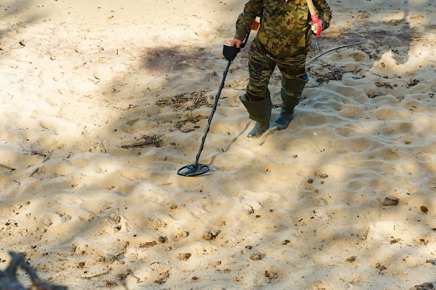 Un hombre con un detector de metales camina al borde del agua de una playa de arena