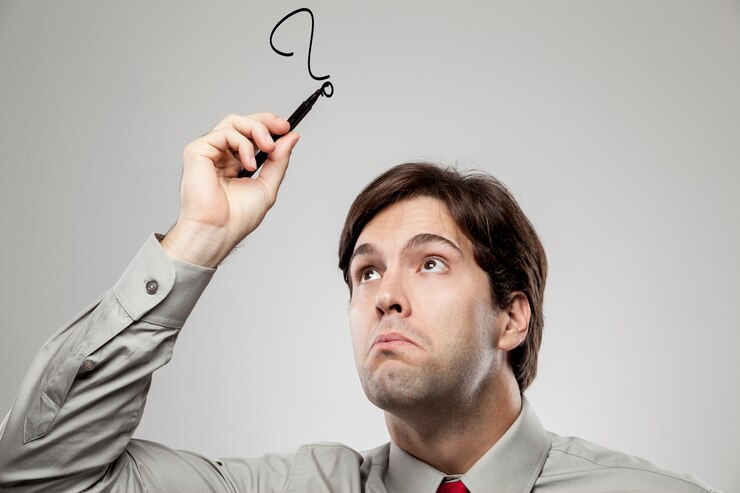 Foto hombre dibujando un signo de interrogación sobre su cabeza, como si tuviera dudas.