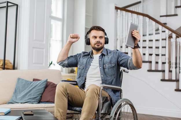 Hombre con discapacidad en auriculares escuchando música en casa