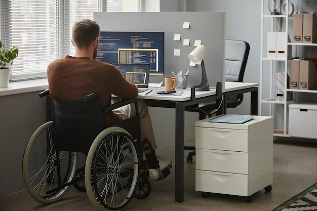 Foto el hombre con discapacidad como programador escribiendo código en la oficina