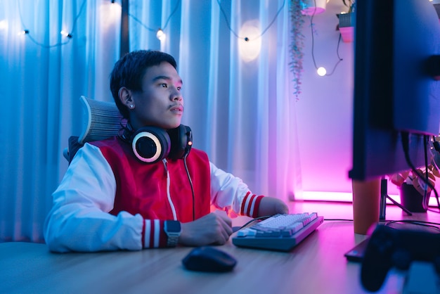 Foto un hombre discapacitado con auriculares se sienta en un escritorio con una luz de neón en el fondo